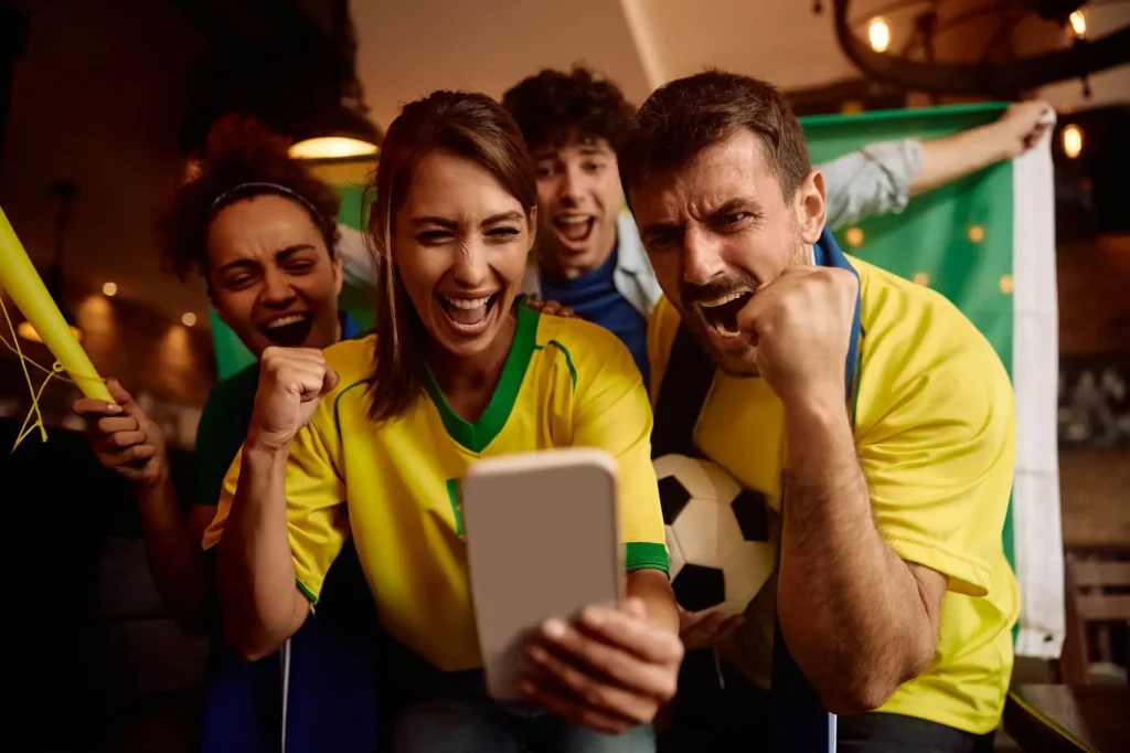 Fans schauen auf eine Fußball App und jubeln dabei
