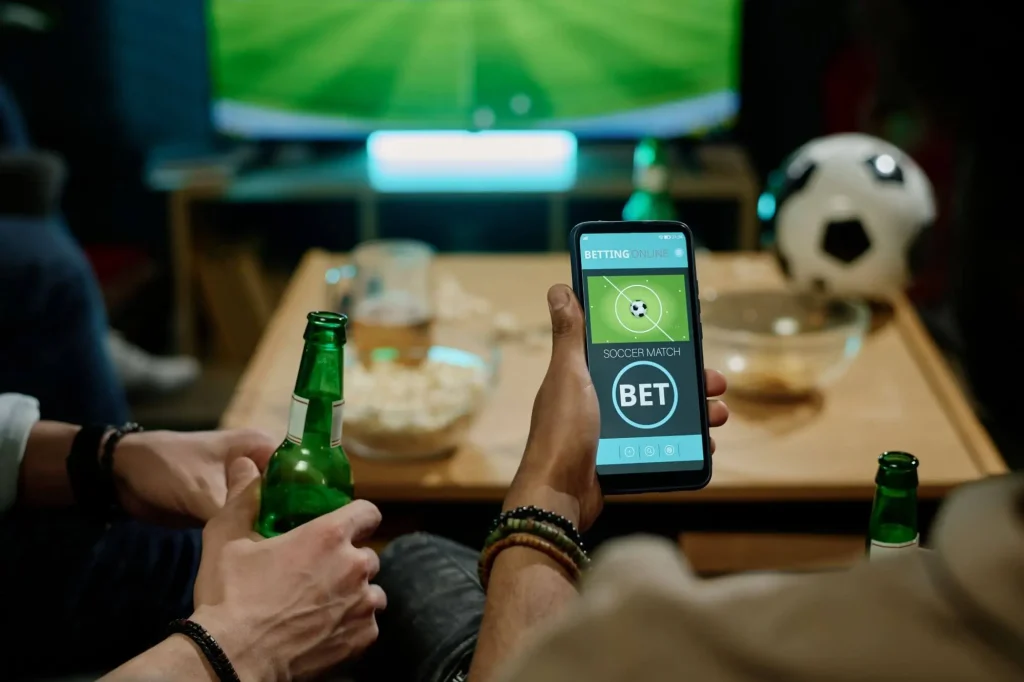 Fans schauen auf eine Fußball App während einem Spiel im TV
