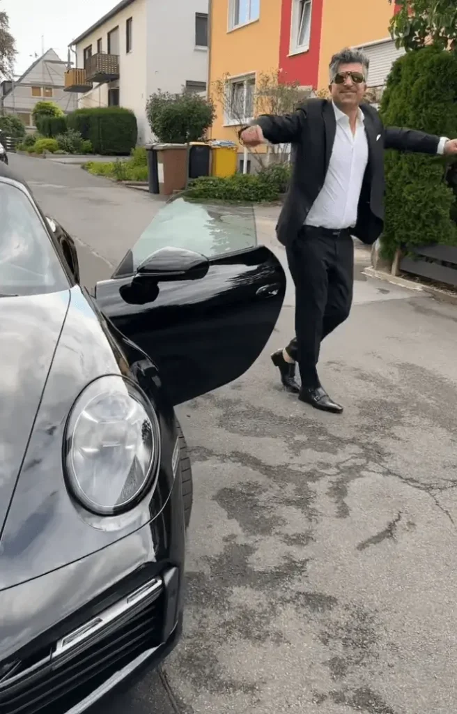 Lotto Millionär Chico tanzt neben seinem Porsche