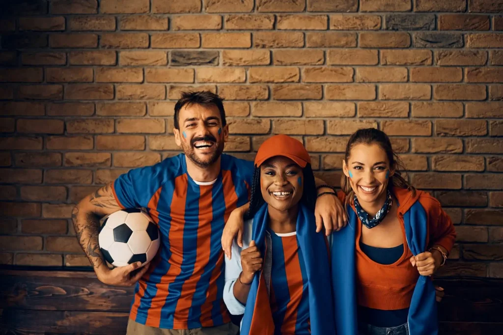 Fans stehen vor einer Steinmauer