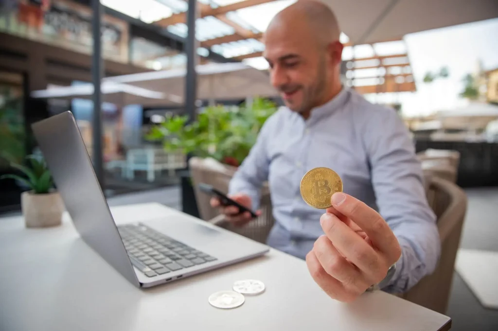 Ein Mann am Laptop mit Bitcoin-Münze