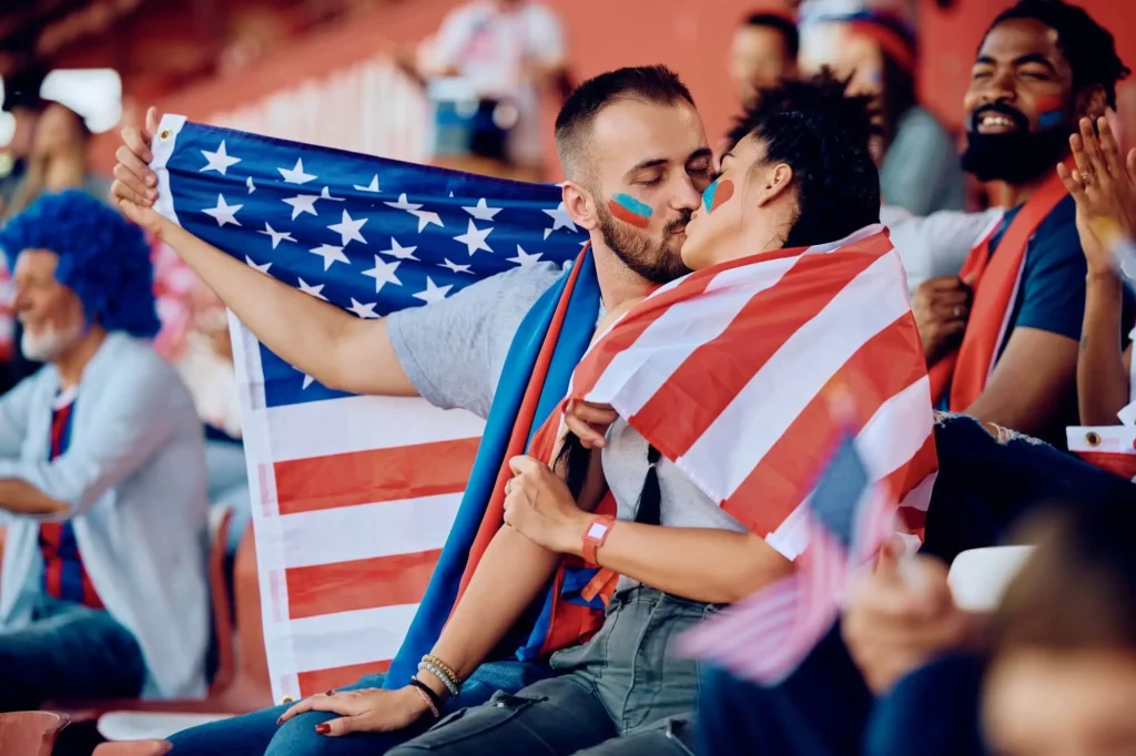 Amerikanische Fans küssen sich auf der Tribüne während eines Spiels