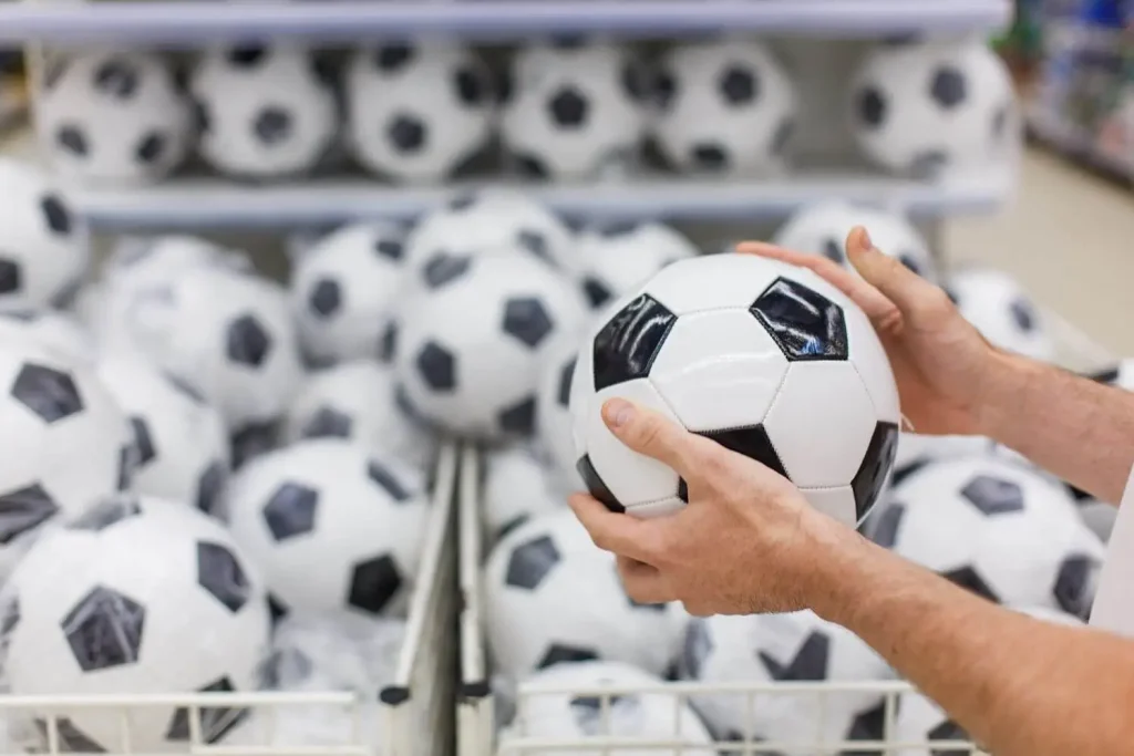 Mann hält einen Ball in einem Fußball Ausrüster Laden