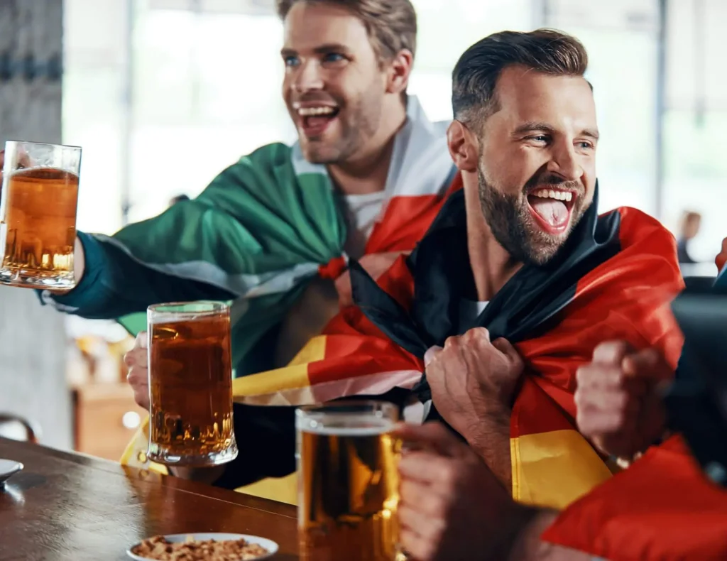 Fans trinken Bier in einer Fußballkneipe und stoßen an