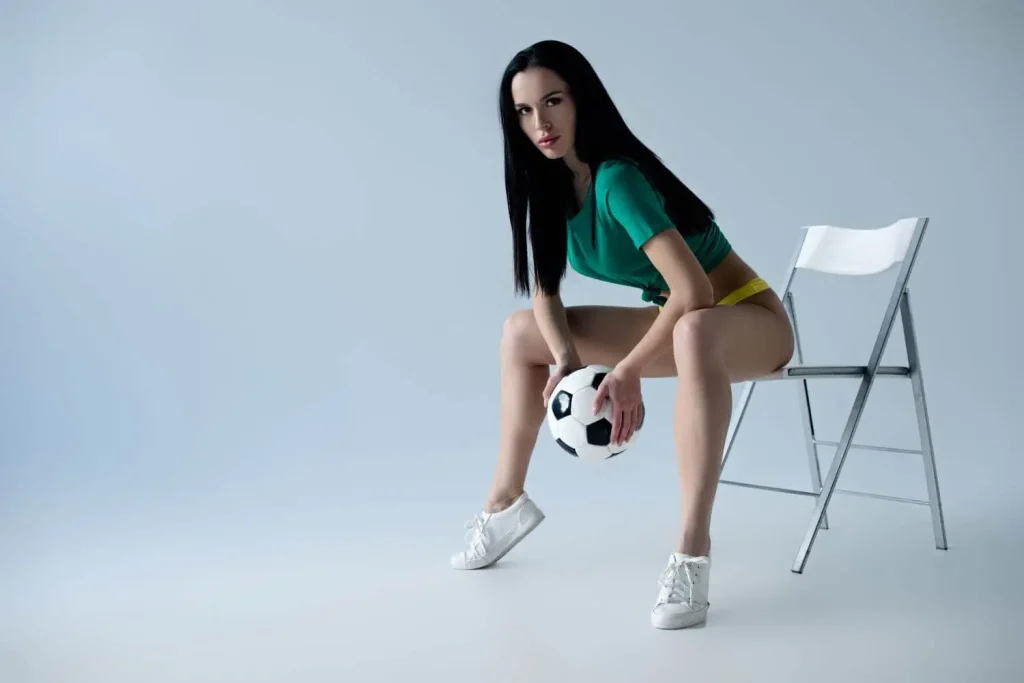 Sexy Fußballerin posiert auf einem Stuhl