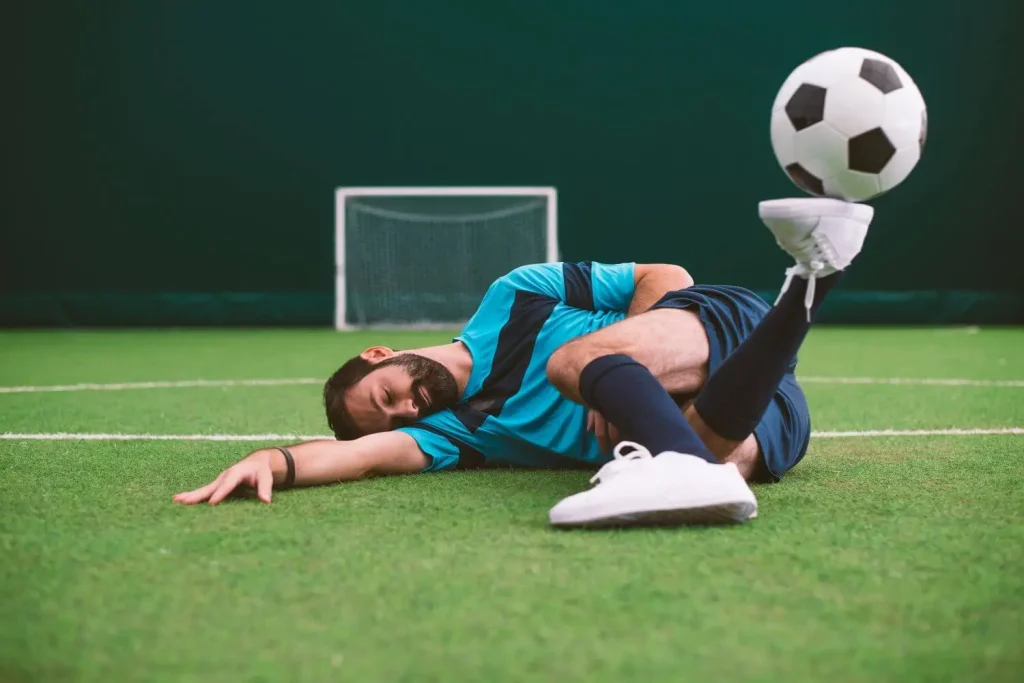 Ein liegender Fußballer mit Ball am Fuß