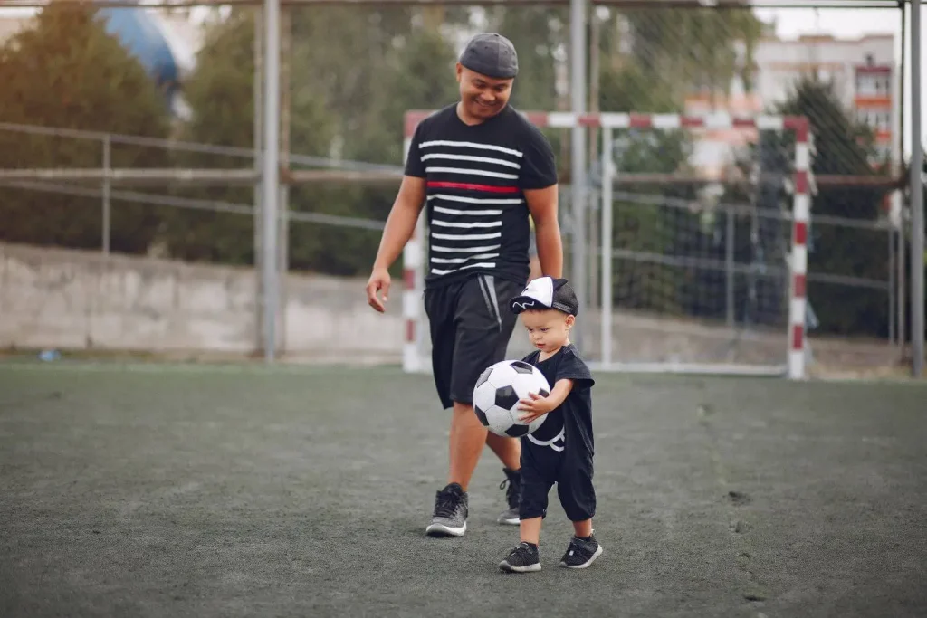 Vater und Sohn beim Fußballspielen am Trainingsplatz