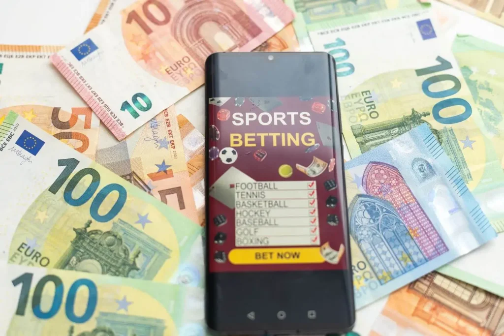 Geldscheine liegen unter einem Smartphone für High Roller Sportwetten
