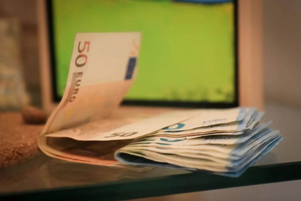 Geldscheine im Fokus mit TV im Hintergrund