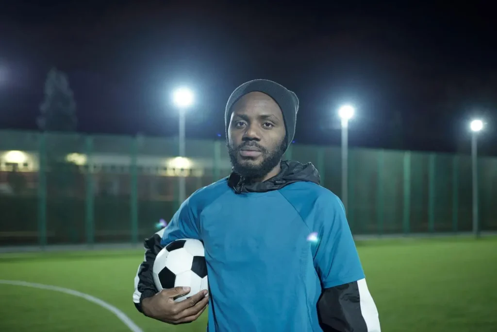 Obdachloser Fußballer mit Ball im Flutlicht