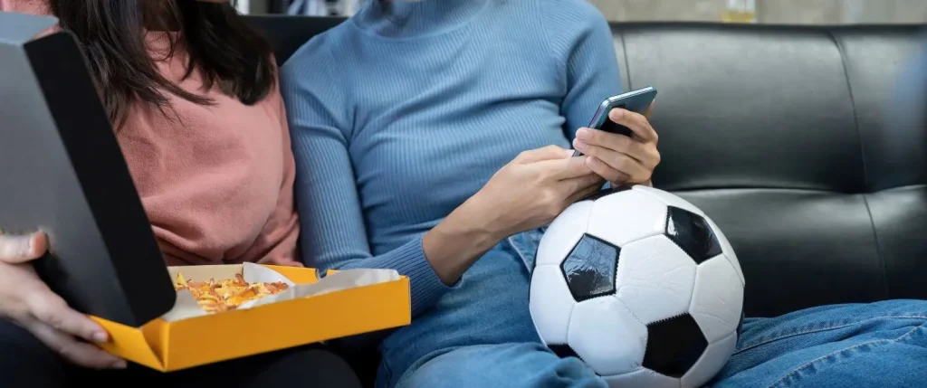 Paar sitzt auf der Couch und wartet auf den Beginn eines Fußballspiels