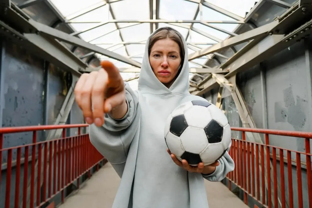 Frau mit Ball zeigt in die Kamera