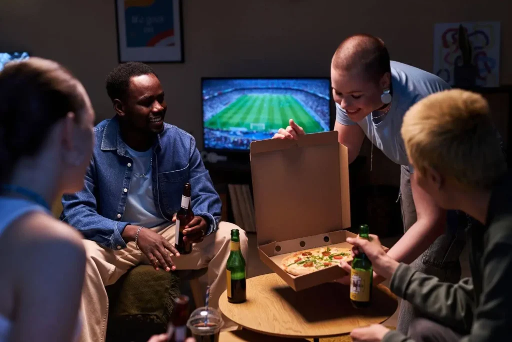 Freunde schauen Fußball und essen Pizza