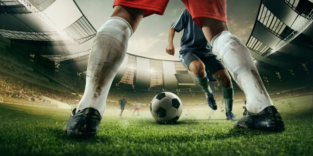 Fußballer beim Dribbling aus der Perspektive auf Höhe des Rasens