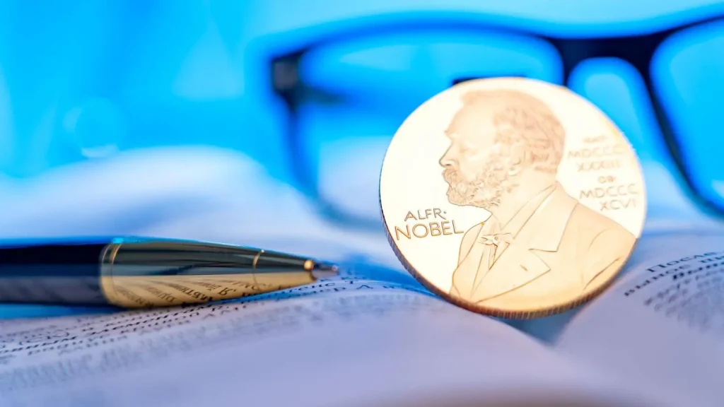 Nobelpreis Medaille liegt auf einem Buch neben einem Stift