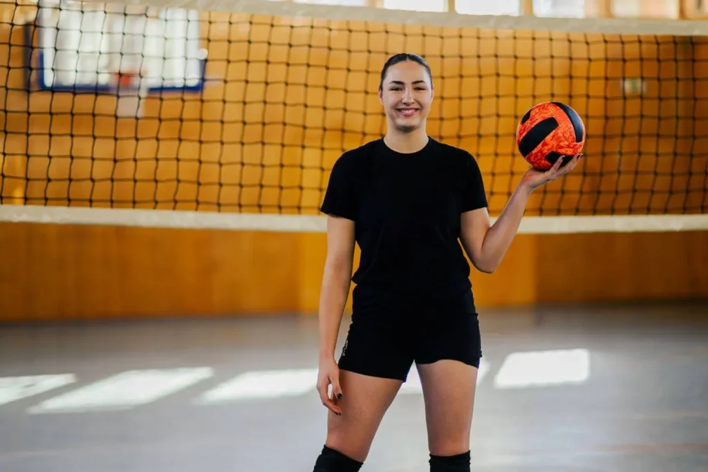 Volleyballspielerin hält einen Ball und steht vor dem Netz