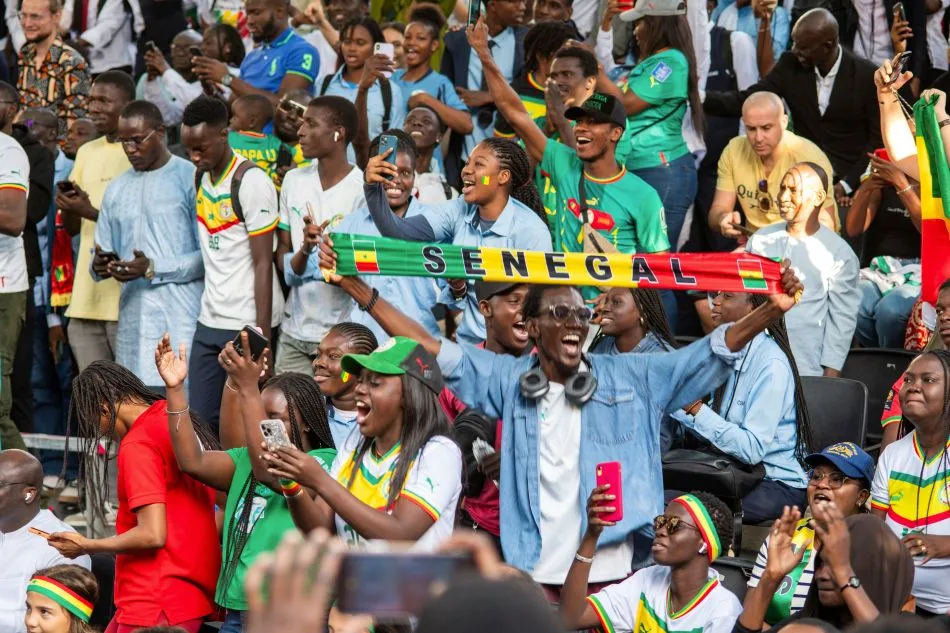 Afrikanische Fußball-Fans auf der Tribüne mit Schals und Nationaltrikots in guter Laune und in Vorbereitung auf den Afrika Cup 2025