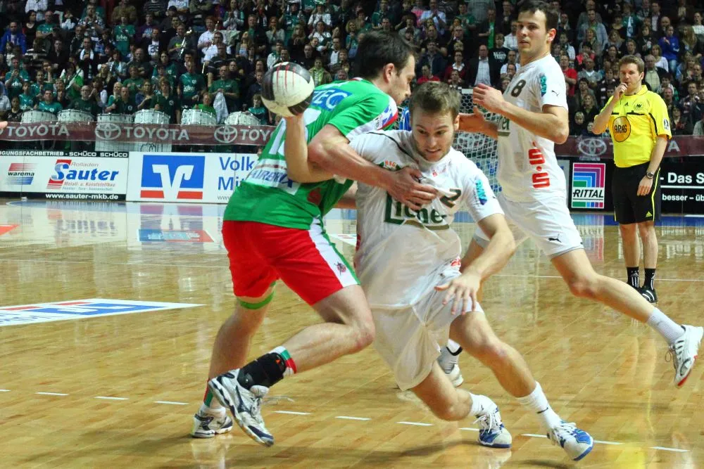 Spieler, der Handball Gehälter kassiert, dribbelt mit dem Ball gegen einen Gegner an