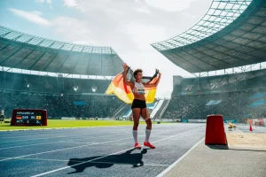 Malaika Mihambo, eine der Favoritinnen bei der Leichtathletik WM 2025, jubelt im Stadion mit der deutschen Flagge