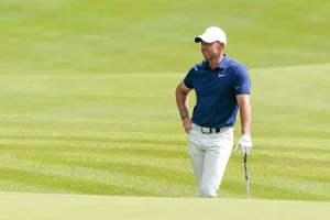 Rory McIlroy, Teilnehmer für Europa beim Ryder Cup 2025, steht lässig an einen Golfschläger angelehnt auf dem Feld
