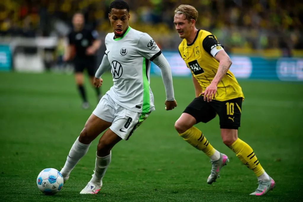 Spieler des VfL Wolfsburg im Trikot des Bundesliga Trikotsponsoren VW im Zweikampf mit einem Spieler von Borussia Dortmund