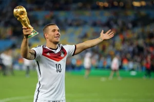 Lukas Podolski jubelt im deutschen Nationaltrikot und mit dem WM-Pokal in der Hand über die gewonnene Fußballweltmeisterschaft