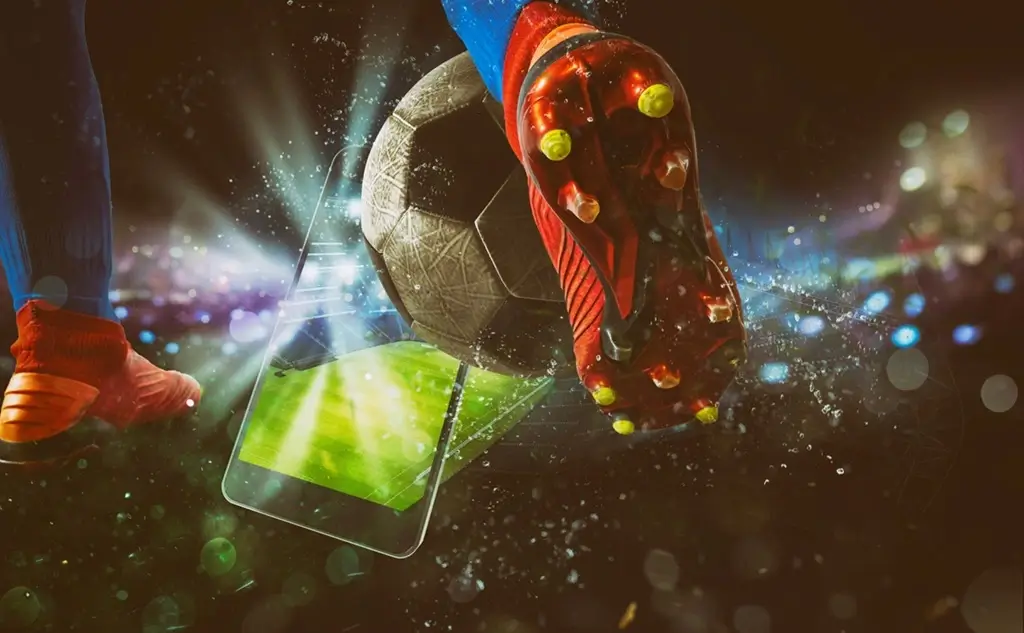 Fussballer setzt im Stadion zum Schuss an. Im Hintergrund ist ein Handy zu sehen.